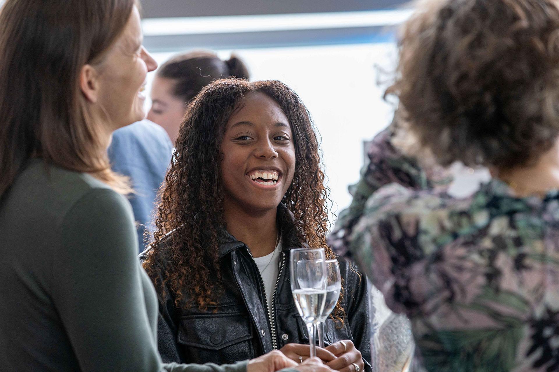 Northern Ballet dancer, Aerys Merrill, smiling broadly wearing a leather jacket and holding a whine glass.